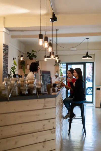两个年轻的女性朋友在咖啡店里和咖啡店里聊天 — 图库照片