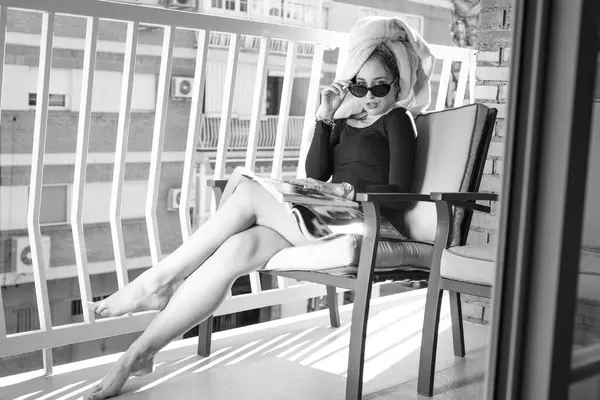 バルコニーで雑誌を読んでいるグラマーの女性眼鏡を手に — ストック写真