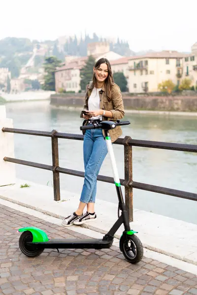 Молода Жінка Орендує Електронний Скутер Тримаючи Свій Смартфон Вероні Італія — стокове фото