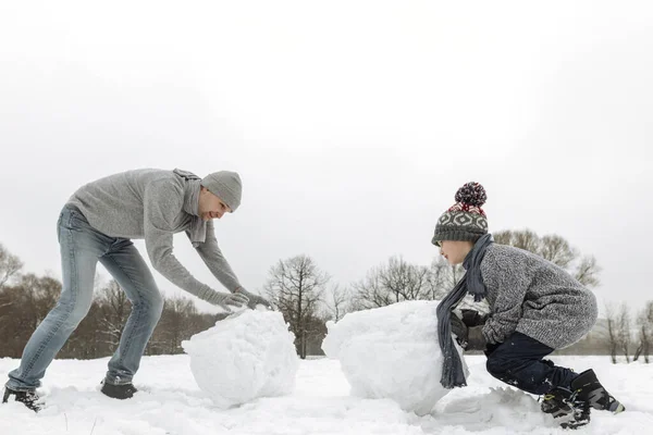 冬の風景の中で雪だるまを作る父と息子 — ストック写真