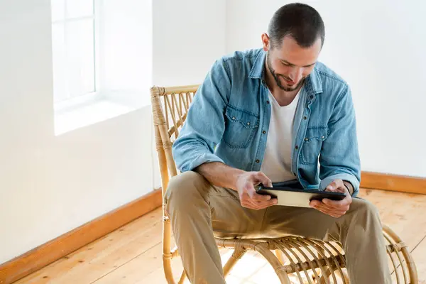 Sonriente Joven Casa Sentado Sillón Madera Delante Ventana Mirando Tableta — Foto de Stock