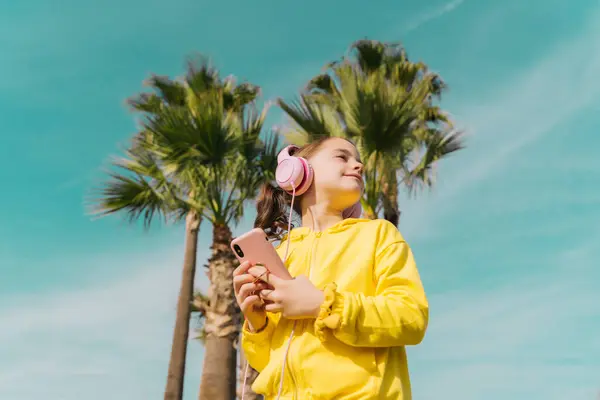 Little Girl Wearing Yellow Jacket Listening Music Headphones Smartphone — Stok fotoğraf