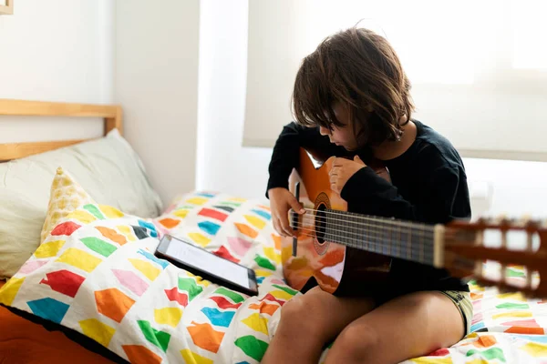 Niño Sentado Cama Usando Tableta Digital Para Tocar Canción Guitarra — Foto de Stock