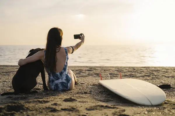 Погляд Молодого Серфера Який Сидить Пляжі Пес Селекціонує Смартфоном Альмерія — стокове фото