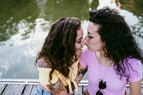 Close Young Woman Kissing Girlfriend Nose While Sitting Lake — Stock Photo, Image