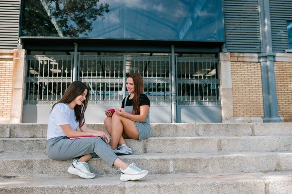 Plná Délka Usmívající Mladé Studentky Mluví Zatímco Sedí Schodech Kampusu — Stock fotografie