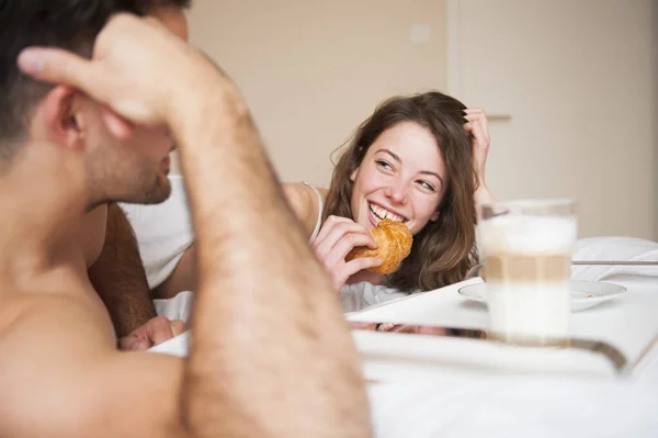 Mujer Feliz Comiendo Croissant Mientras Mira Hombre Dormitorio — Foto de Stock