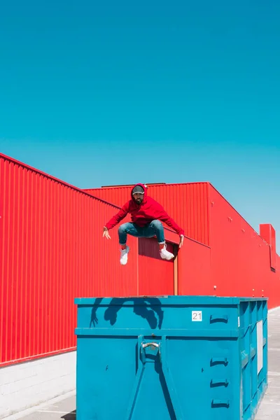 Young Man Wearing Red Hooded Jacket Jumping Edge Container Front — Stock Photo, Image