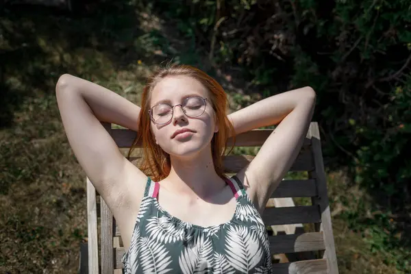 一位年轻女子在花园里的躺椅上日光浴的画像 — 图库照片