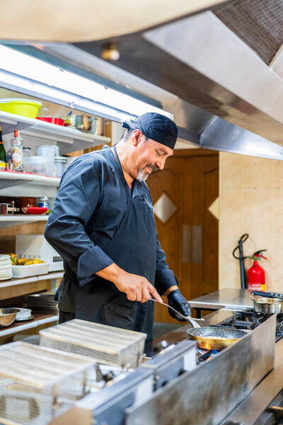 Chef with pan in traditional Spanish restaurant kitchen