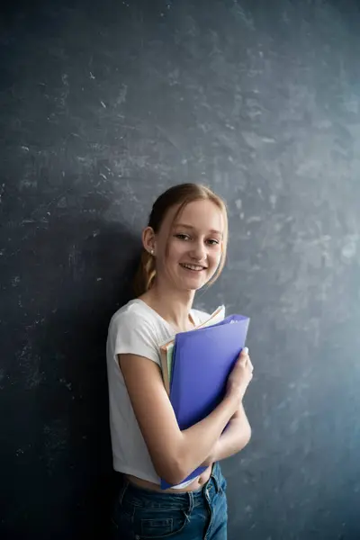 Dziewczyna Książkami Wysiłku Przed Czarną Ścianą — Zdjęcie stockowe