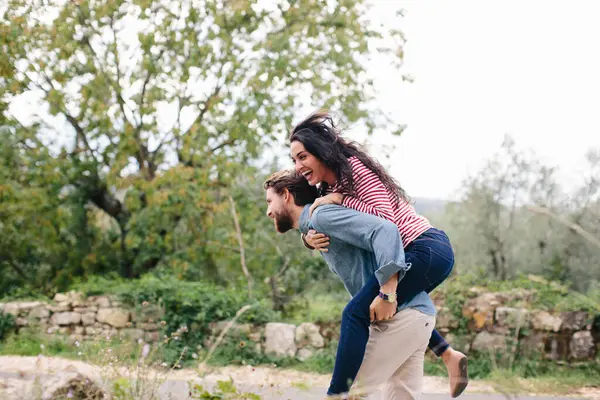 ハッピー男Piggybackingガールフレンドながら屋外で実行 — ストック写真