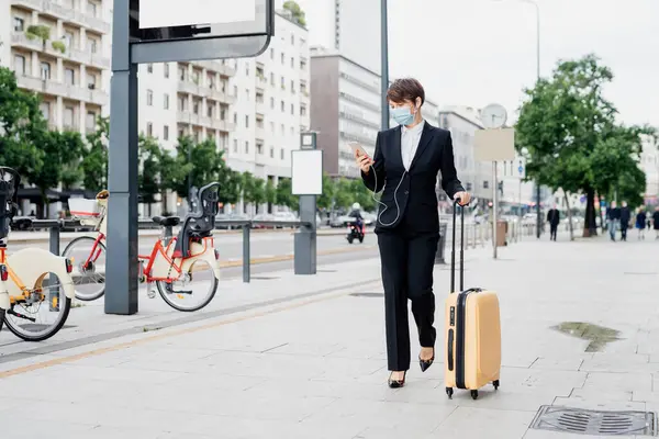 Businesswoman Wearing Mask Using Smart Phone While Walking Suitcase Sidewalk — Stok fotoğraf