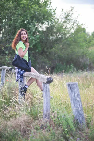 Junge Frau Sitzt Auf Beschädigtem Holzzaun Feld — Stockfoto