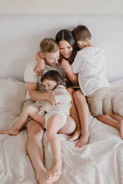 Sonrientes Padres Abrazando Los Niños Mientras Están Sentados Cama Dormitorio —  Fotos de Stock