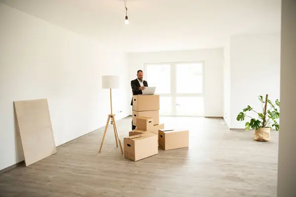 Geschäftsmann Arbeitet Neuer Wohnung Über Laptop Gestapelten Kisten — Stockfoto
