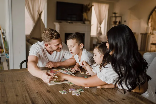 Glimlachende Ouders Oplossen Puzzel Met Kinderen Tafel Thuis — Stockfoto