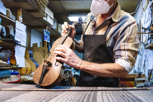 Handwerker Mit Mundschutz Begutachtet Geige Auf Werkbank Werkstatt — Stockfoto