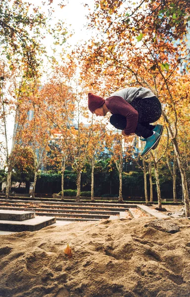 Молодой Человек Прыгает Песку Обнимая Колени Парке — стоковое фото