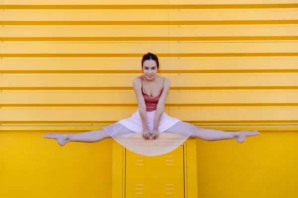 Young Woman Doing Splits While Ballet Dancing Seat Yellow Wall — Stock Photo, Image