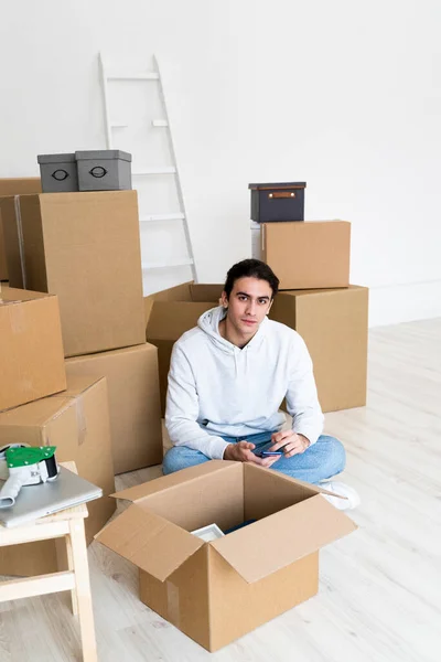 Jovem Com Telefone Celular Sentado Por Caixas Papelão Novo Apartamento — Fotografia de Stock