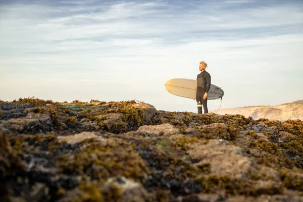 Surfer Steht Mit Surfbrett Auf Felsformation Strand Gegen Den Himmel — Stockfoto