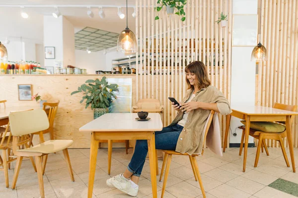 Glimlachende Zakenvrouw Sms Smartphone Tijdens Het Zitten Cafe — Stockfoto