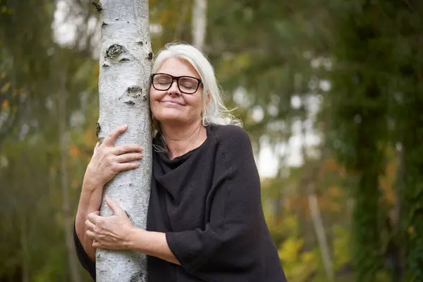 Улыбающаяся Пожилая Женщина Закрытыми Глазами Обнимающая Ствол Дерева Общественном Парке — стоковое фото