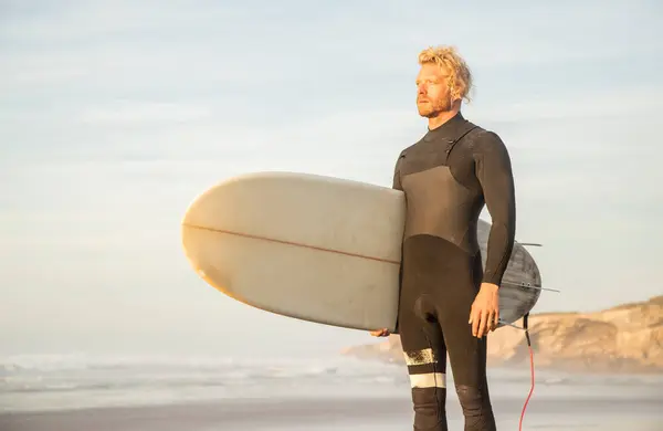 Blond Man Wearing Wetsuit Carrying Surfboard While Looking Away Beach — Stock Photo, Image