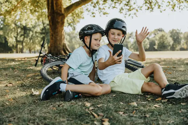 Kardeşler Parkta Otururken Akıllı Telefondan Video Görüşmesi Yapıyor — Stok fotoğraf