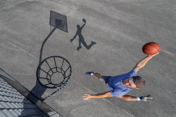 Jovem Homem Dunking Bola Aro Enquanto Joga Basquete Dia Ensolarado — Fotografia de Stock