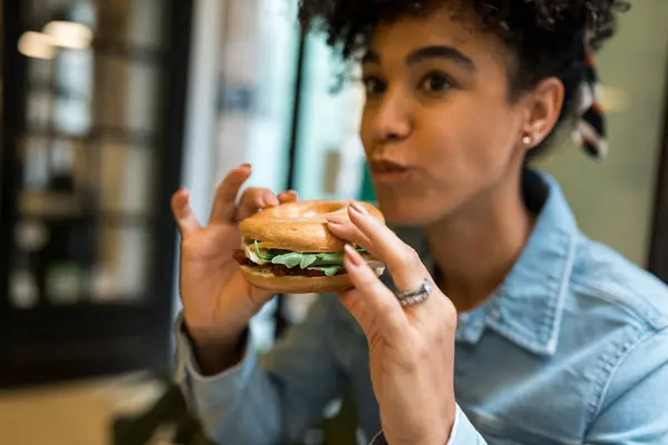 Mid Adult Woman Eating Burger While Sitting Cafe — Stock Photo, Image