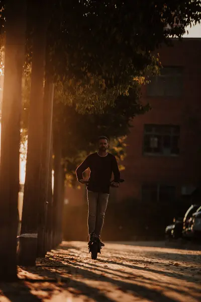 Mann Fährt Elektroroller Bei Sonnenuntergang Der Stadt — Stockfoto