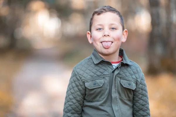 Мальчик Высовывает Язык Стоя Парке Осенью — стоковое фото