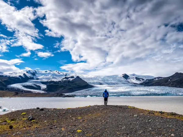 アイスランドのBreidamerkurjokullで曇った空に対して山からの眺めを見る男 — ストック写真