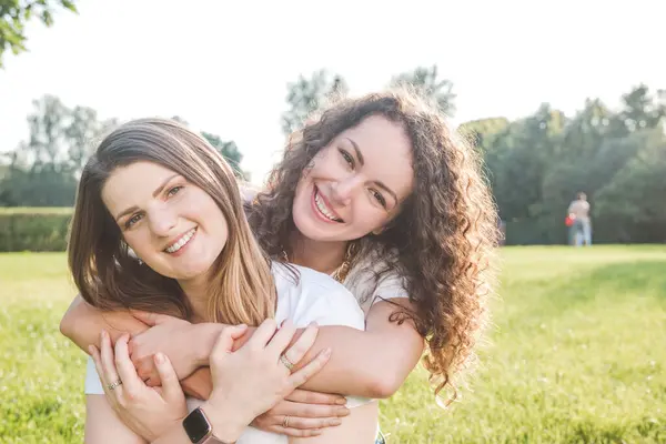 Sorrindo Jovem Mulher Abraçando Amigo Feminino Trás Parque Dia Ensolarado — Fotografia de Stock