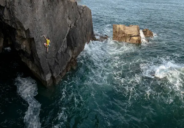年轻的男性攀岩者攀岩于大海之上 — 图库照片