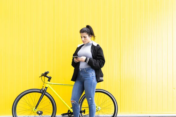 Güzel Bir Kadın Sarı Duvarın Önünde Dikilirken Akıllı Telefon Kullanıyor — Stok fotoğraf