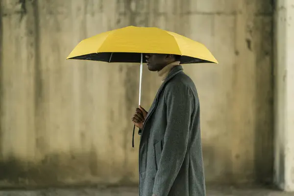 Young Man Holding Yellow Umbrella While Standing Wall — 스톡 사진