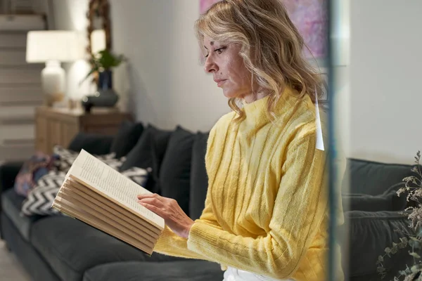 Mulher Madura Camisola Amarela Leitura Livro Sofá Casa — Fotografia de Stock