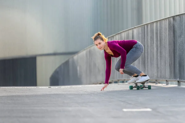 年轻女子在人行天桥上滑板 — 图库照片