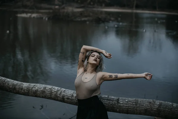 Mladá Žena Opírající Padlý Strom Proti Jezeru — Stock fotografie