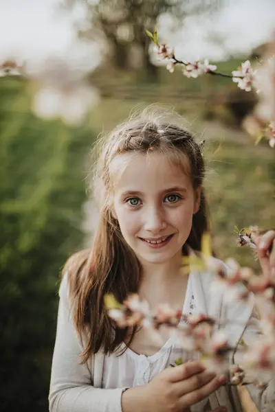 アーモンドの木の花が立っている間に微笑むかわいい女の子 — ストック写真