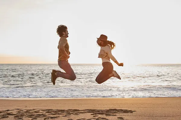 日出时在海滩上跳着玩的情侣 — 图库照片