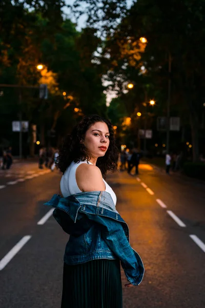 夕暮れ時にストリートに立ちながらデニムジャケットを着た美しい女性 — ストック写真