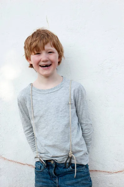 Ευτυχισμένο Κοκκινομάλλικο Αγόρι Στέκεται Μπροστά Από Λευκό Τοίχο — Φωτογραφία Αρχείου