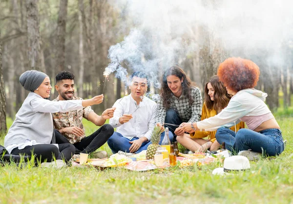 Playful Male Female Friends Holding Sparkler While Sitting Forest — Stock Photo, Image