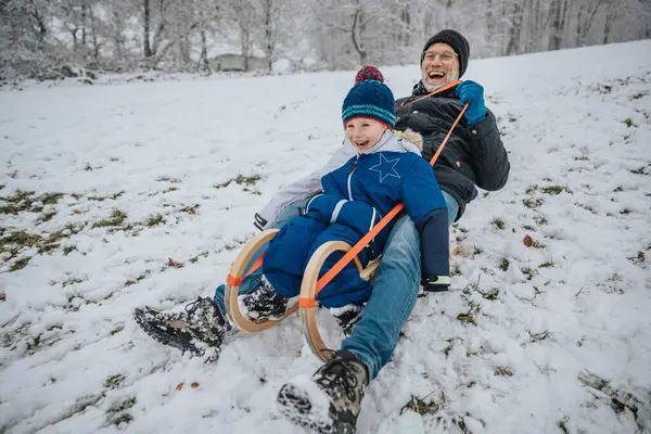 冬天快乐的父子俩从雪山滑下 — 图库照片