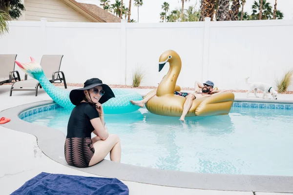 Smiling Woman Sitting Poolside While Man Relaxing Inflatable Swan Sunny — Stock Photo, Image