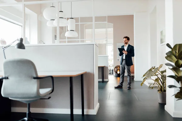 Zakenman Met Digitale Tablet Kijkt Weg Terwijl Hij Kantoor Staat — Stockfoto